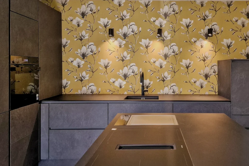 Moderne Küchenzeile mit dunkelgrauen Schränken, Küchenrückwand mit Blumenmuster und Kochfeld