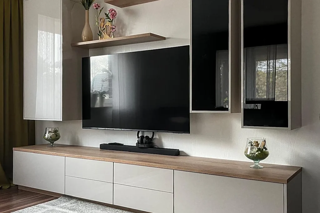 Moderne Küchenzeile mit weißem Unterschrank, Holzarbeitsplatte, eingebautem TV und großen Fenstern.