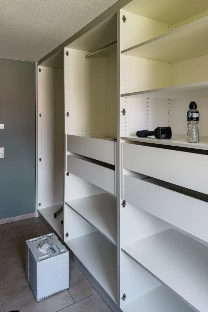 Einbauschrank in der Küche mit offenen Regalen und Schubladen; unten steht eine Geschirrspülmaschine.