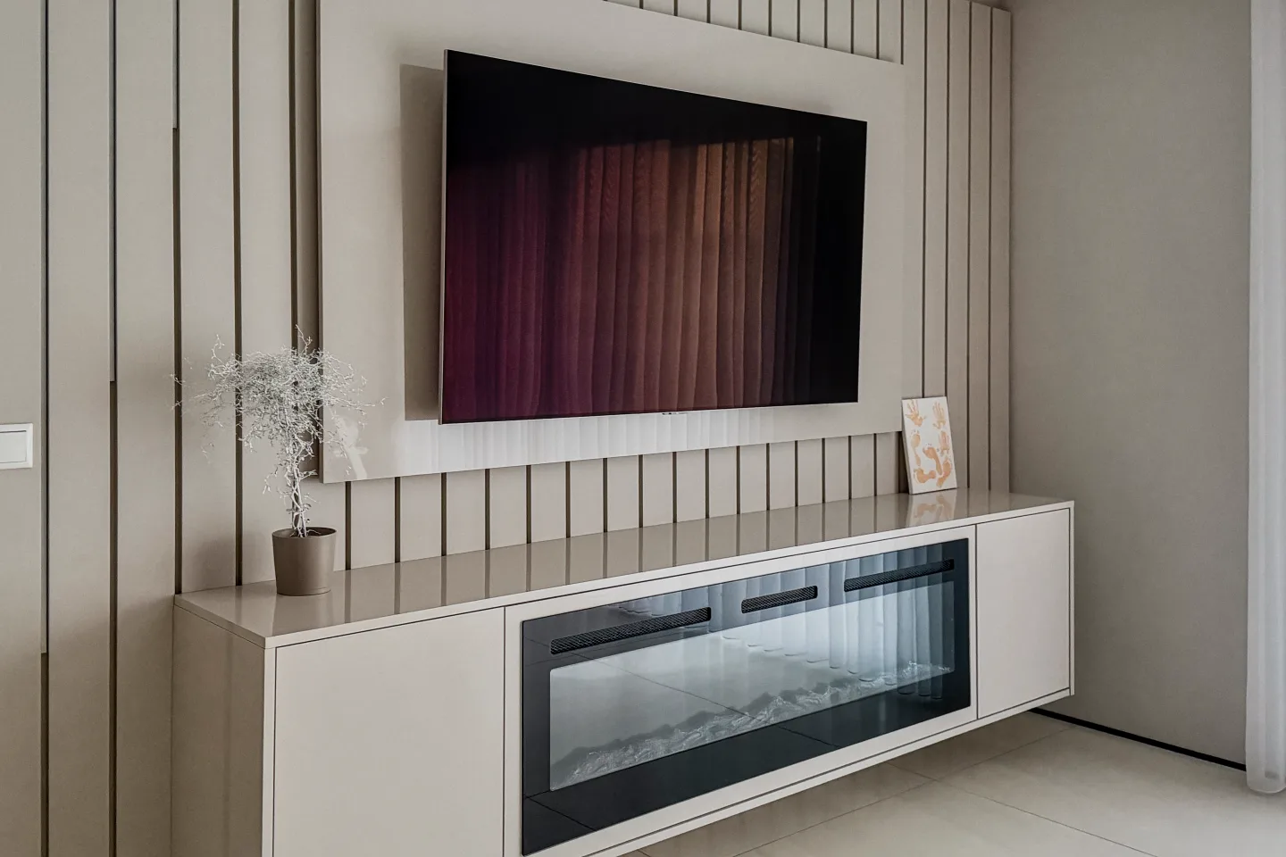 Weiße Einbauküche mit großem TV im Wandnischenschrank und Glastür des Backofens