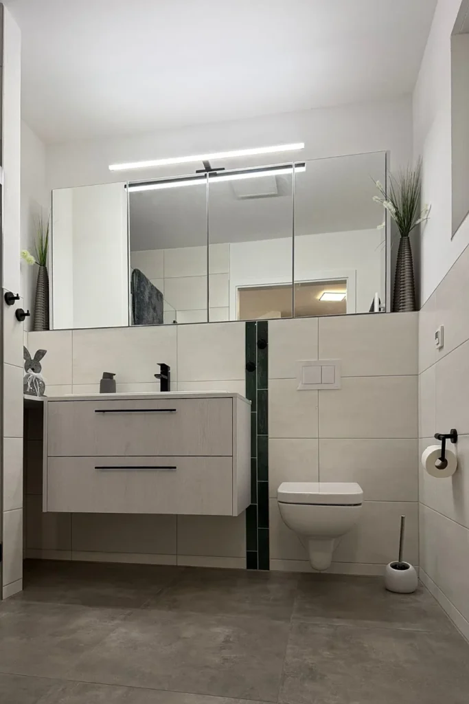 Waschtischunterschrank mit großem Spiegel, Armatur und Toilette im modernen Badezimmer