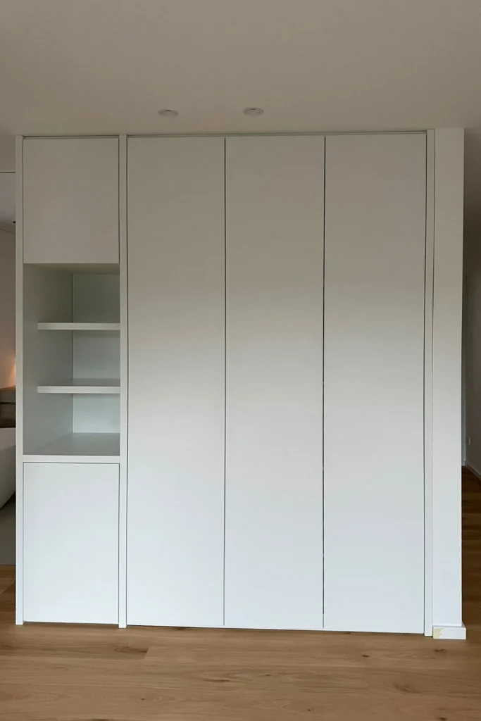 Weißer Schrank mit Schiebetüren und offenem Regalfach, im Wohnbereich