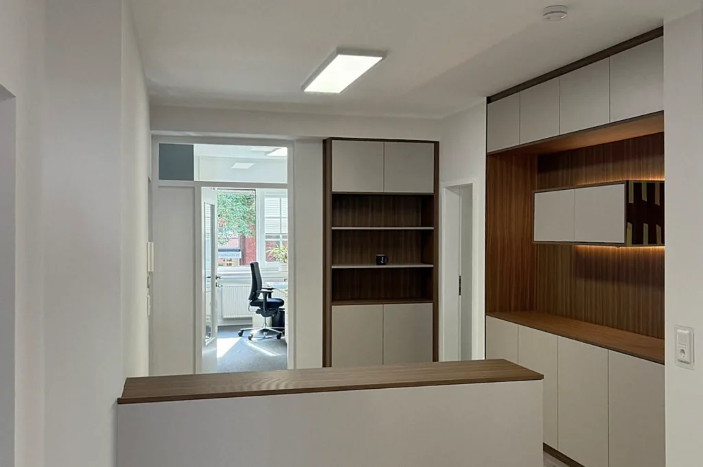 Moderne Einbauküche mit Oberschränken, Nischenregal und Holzfronten, Blick durch die Tür ins Büro