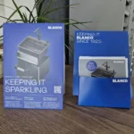 Zwei blaue BLANCO-Produktverpackungen mit „KEEPING IT SPARKLING“, „KEEPING IT BLANCO SINCE 1925“ und Armaturabbildung