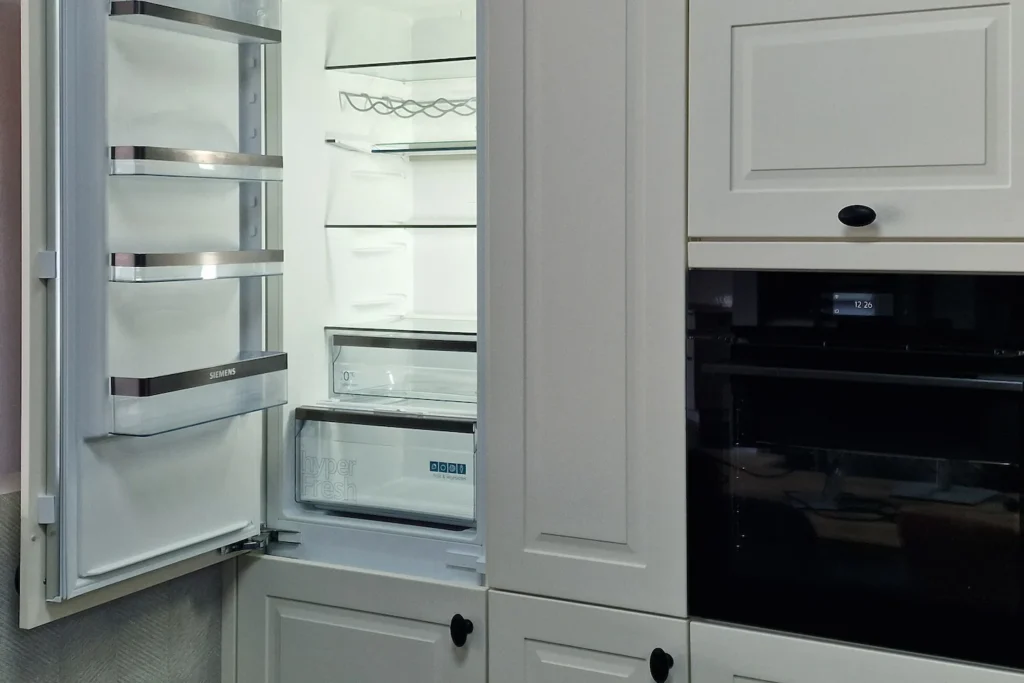 Einbau-Kühlschrank mit Tür und integrierter Backofen mit Display in einer hellen Küchenzeile