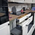 Küchenzeile mit Backofen, Herdfläche und offenem Schubladenschrank auf Holz-Arbeitsplatte