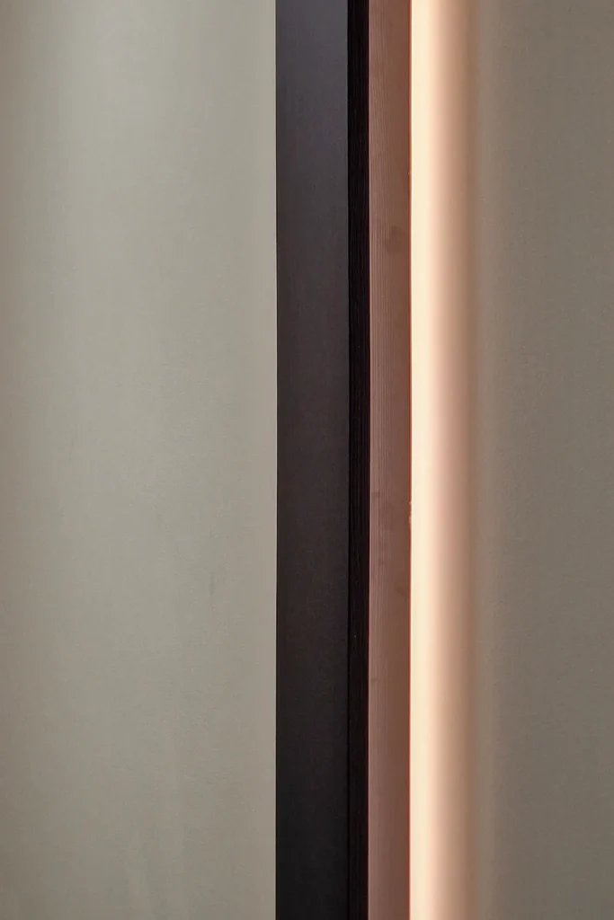 Schmale Nische mit dunkler Einfassung, Holzleiste und integrierter LED-Lichtkante an der Wand
